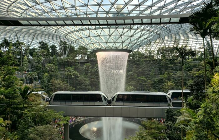 train near trees inside building with indoor waterfalls